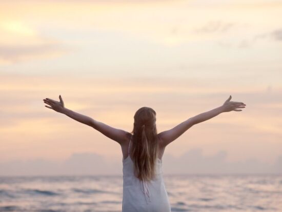 Co składa się na szczęście? NA zdjęciu szczęśliwa kobieta rozkłada ręce.