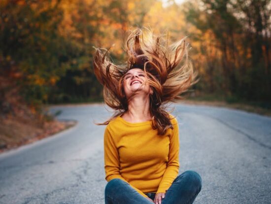 Czy radość to szczęście? Na zdjęciu radosna kobieta na ulicy.