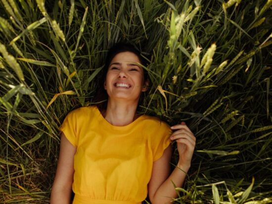 Czy radość to emocja? na zdjęciu radosna kobieta w trawie.
