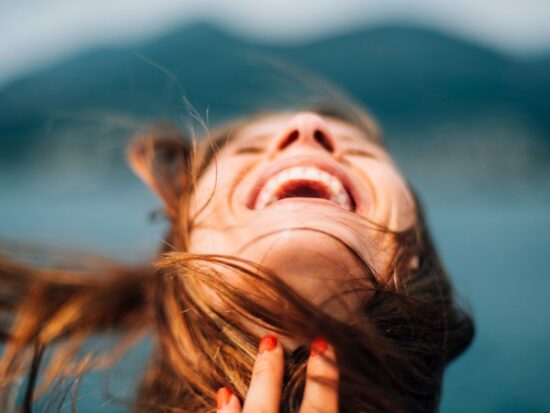 Jak uczucie radości wpływa na człowieka? Na zdjęciu radosna kobieta.