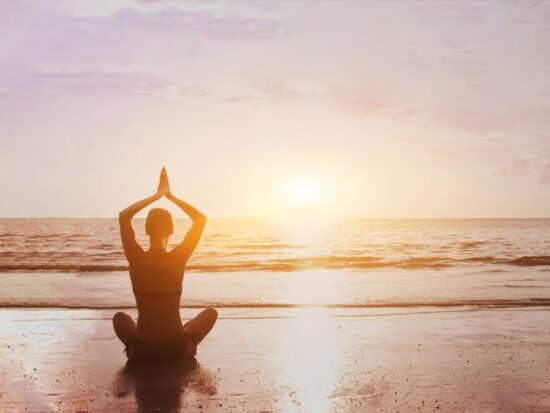 Czy mindfulness to grzech? Na zdjęciu kobieta medytuje na plaży.