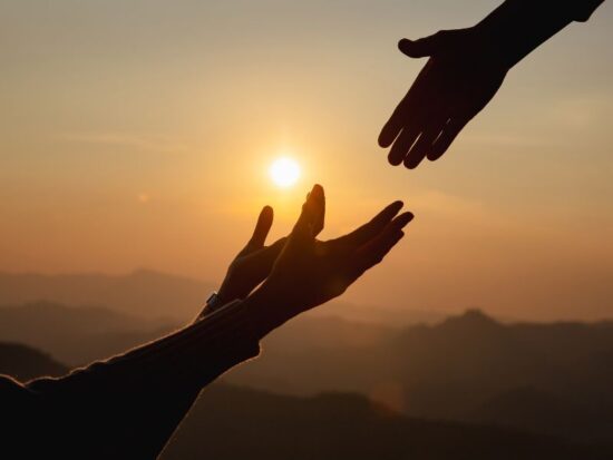 Wiara Jehowa – czym jest i jak się narodziła? Na zdjęciu dłonie na tle zachodzącego słońca.